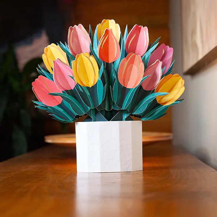 Ein weißer Umschlag zum Aufbewahren des gefalteten Straußes und ein Kärtchen zum Schreiben einer Nachricht liegen bei.